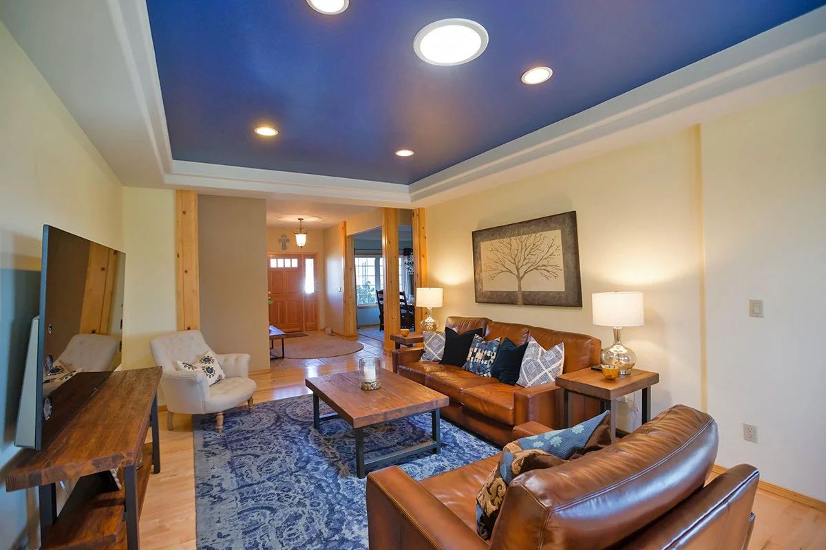 Living room with navy tray ceiling, leather sofas and blue rug