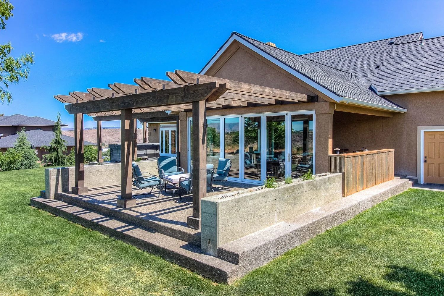 Wood pergola over a patio beside a covered sunroom