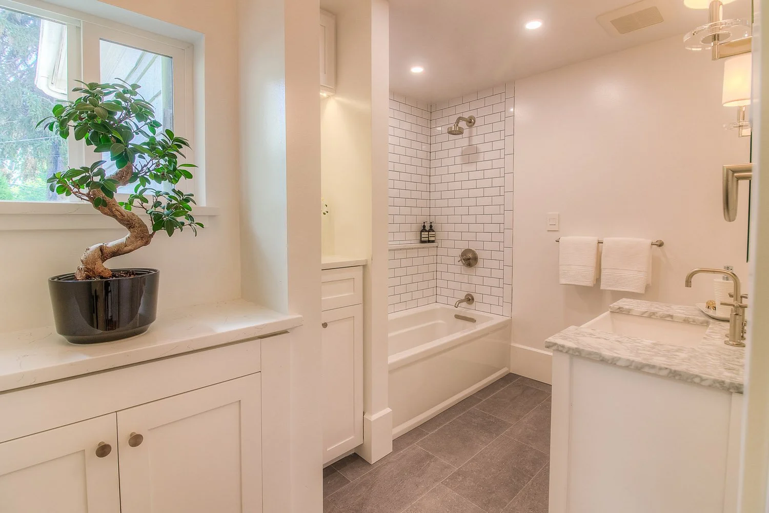 Bathroom with white cabinets, window and potted bonsai
