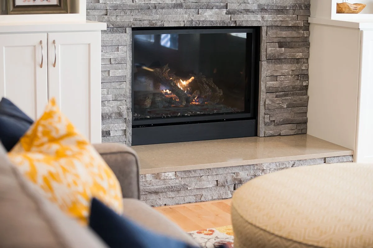 Gas fireplace with stacked stone surround and stone hearth