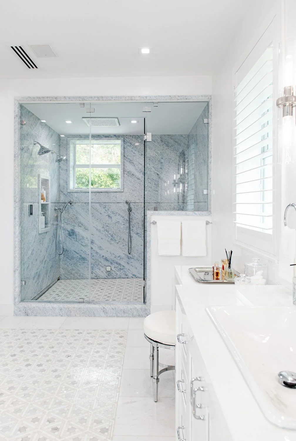 Bathroom with glass shower, marble floor and white vanity