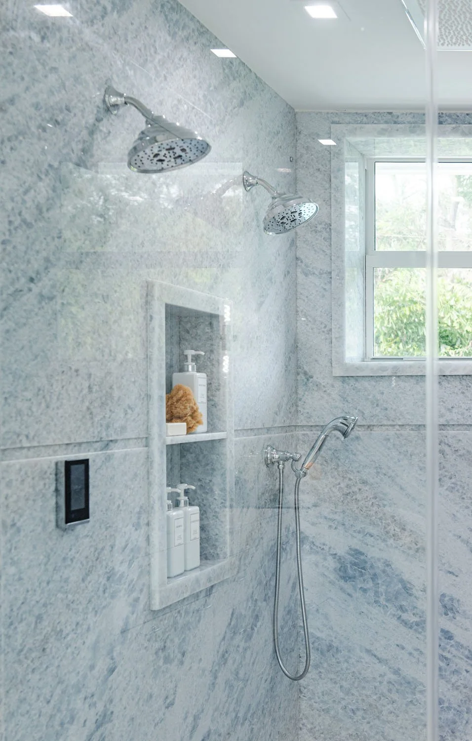 Walk-in shower with gray marble walls and built-in niche