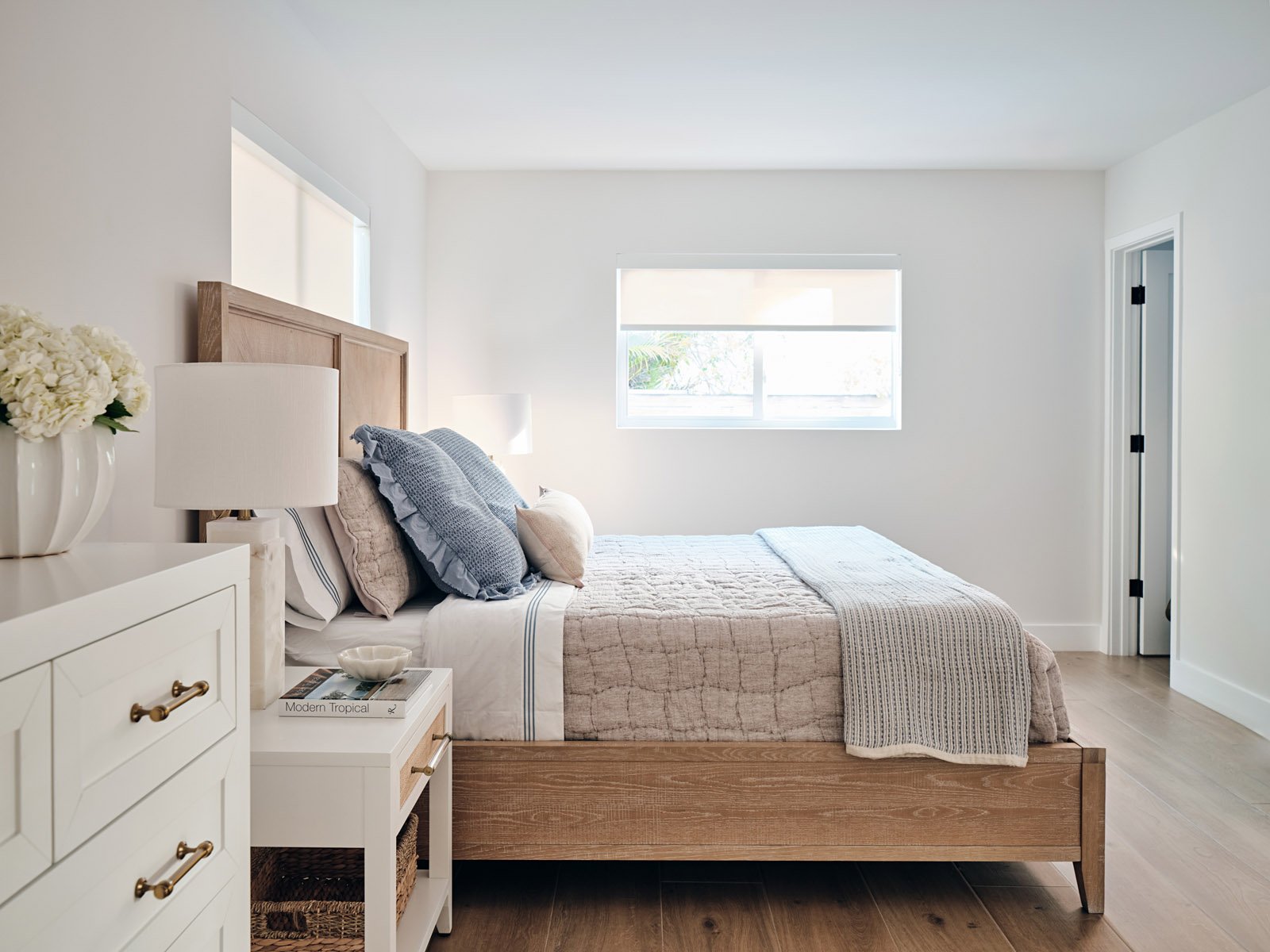 Bedroom with upholstered bed, white nightstand and window