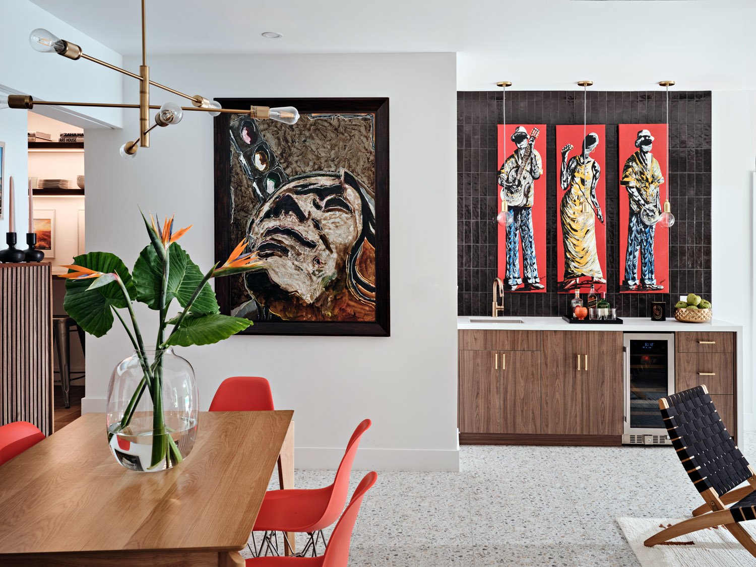 Dining area with coral chairs and walnut bar cabinet with red artwork