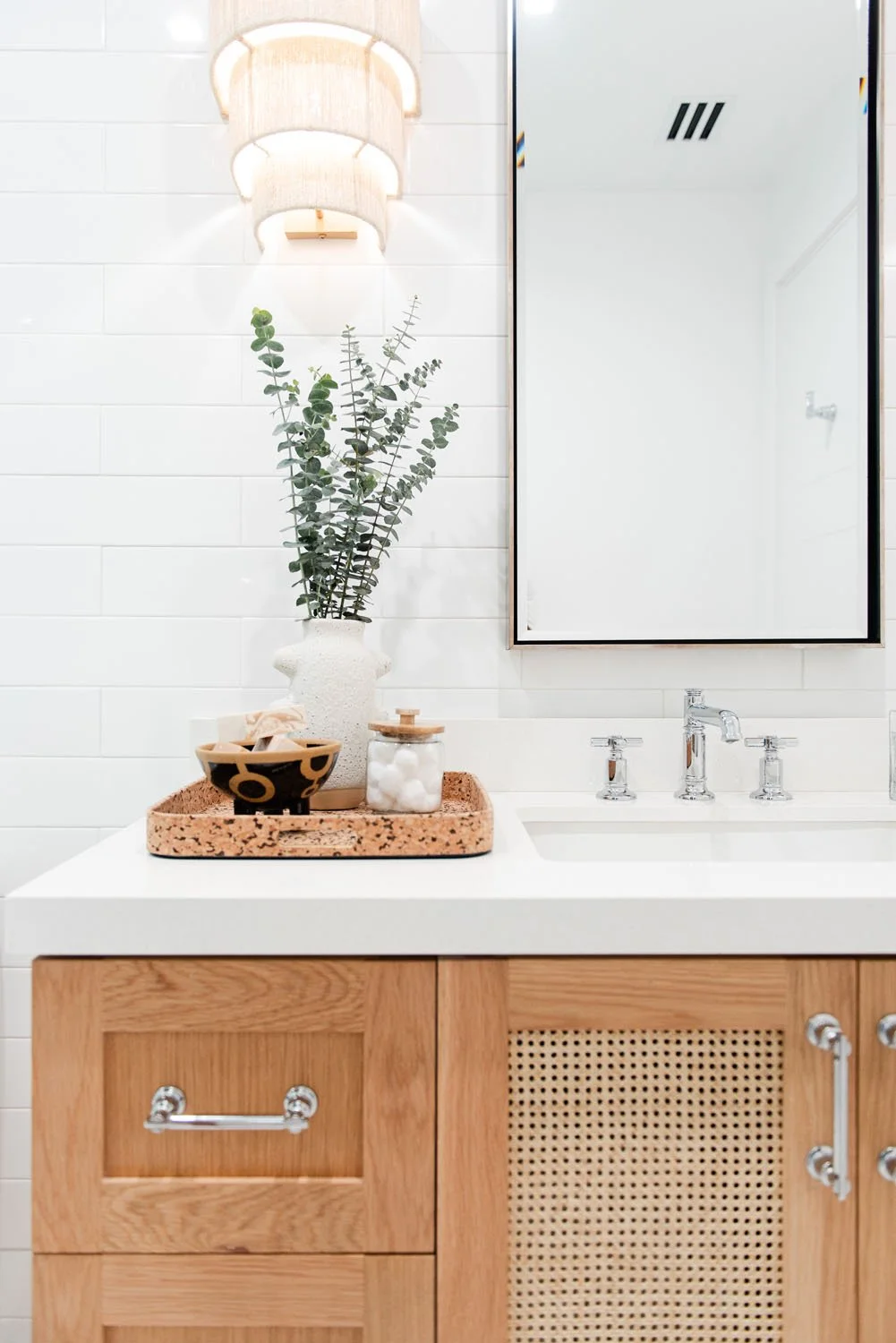 Light wood vanity with cane door fronts and black framed mirror