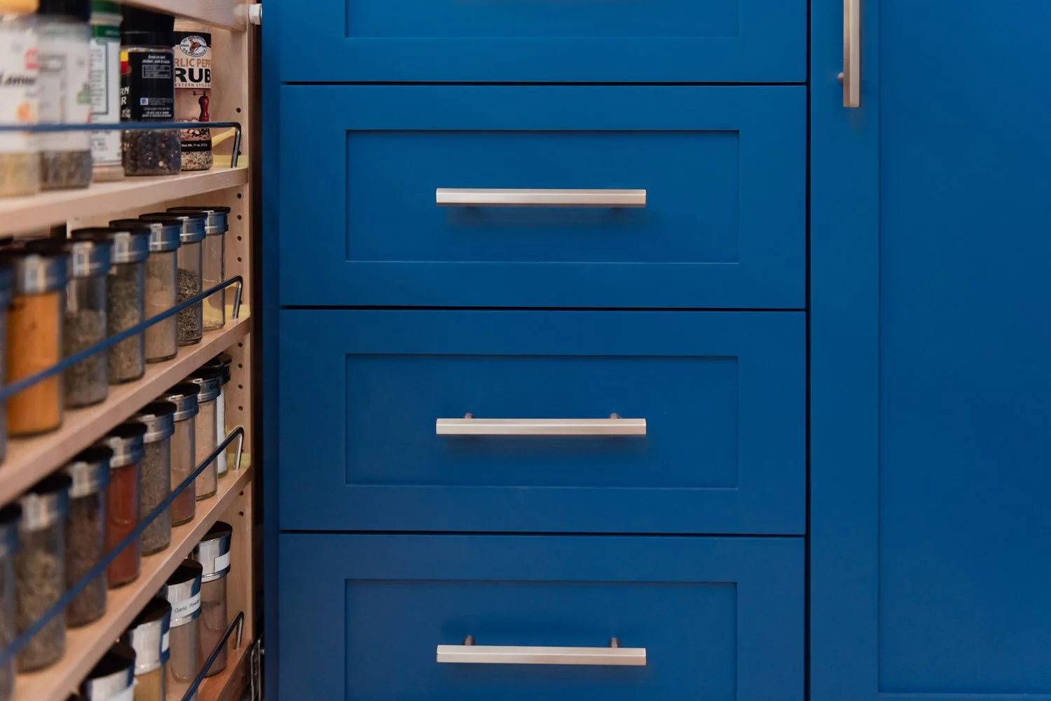 Navy cabinets with brushed nickel pulls beside pantry storage