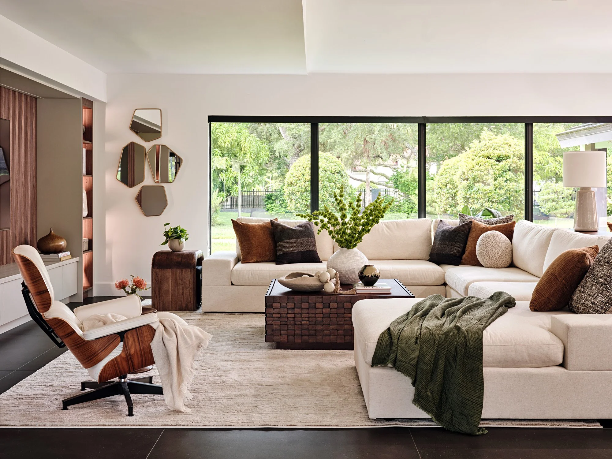 Living room with white sectional, leather lounge chair and wall of windows