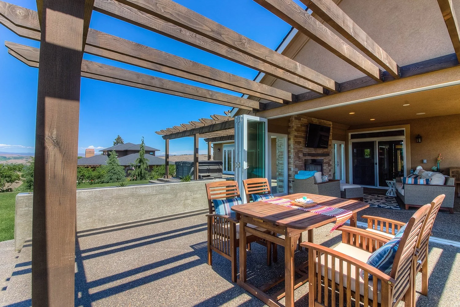 Outdoor dining table with wood chairs under a pergola