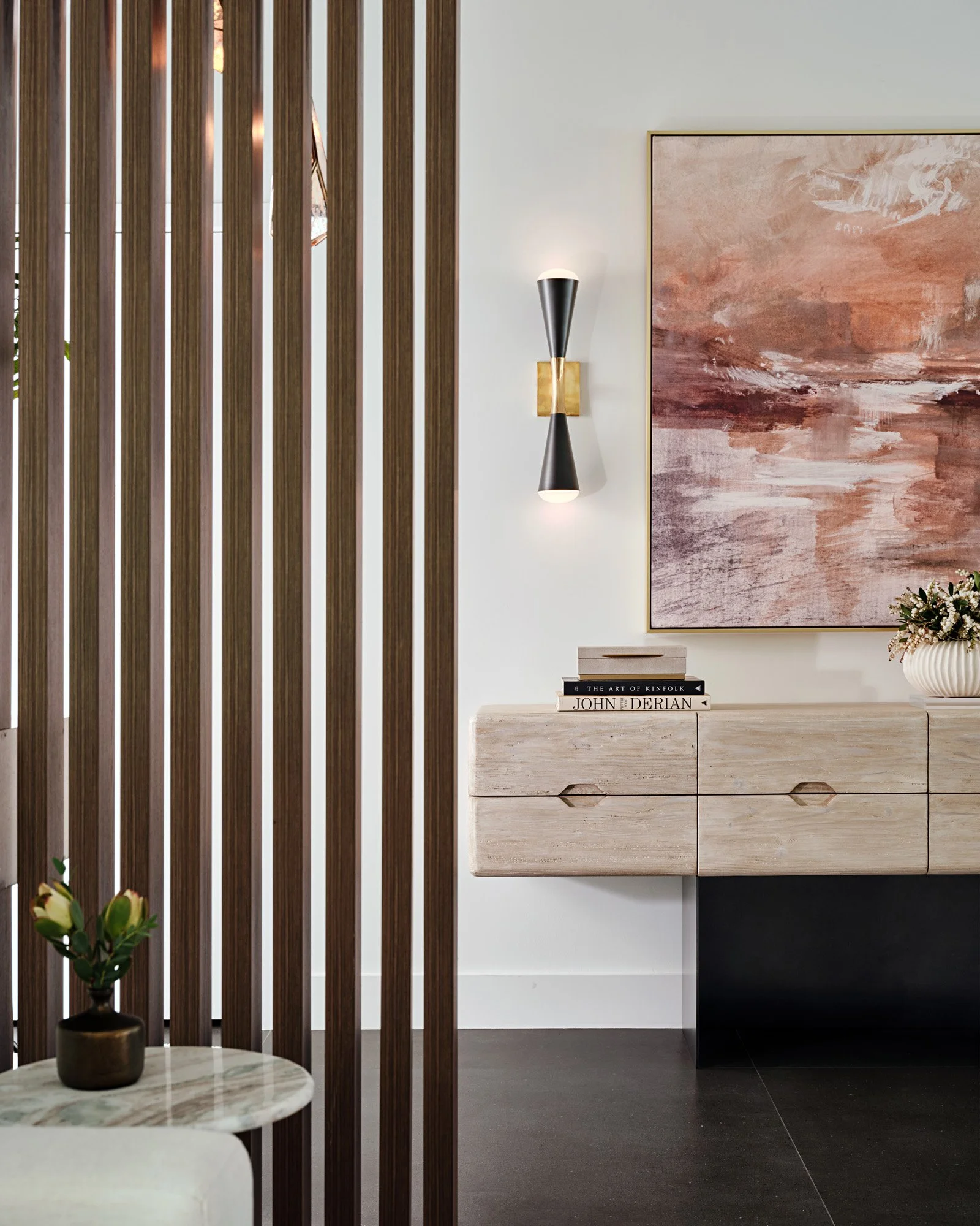 Foyer with walnut slat divider, floating console and abstract art