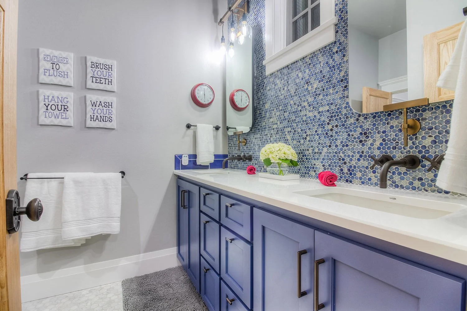 Navy vanity with mosaic tile backsplash and wall sconces