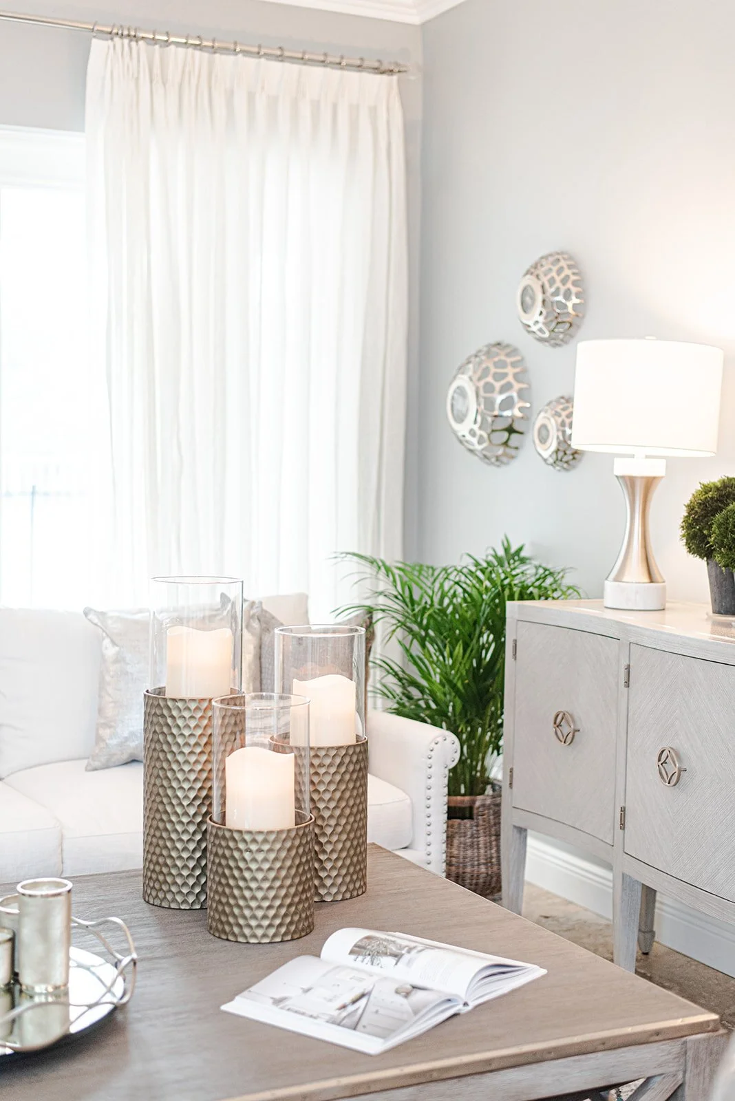 Gold candle holders on a console with table lamp and plant