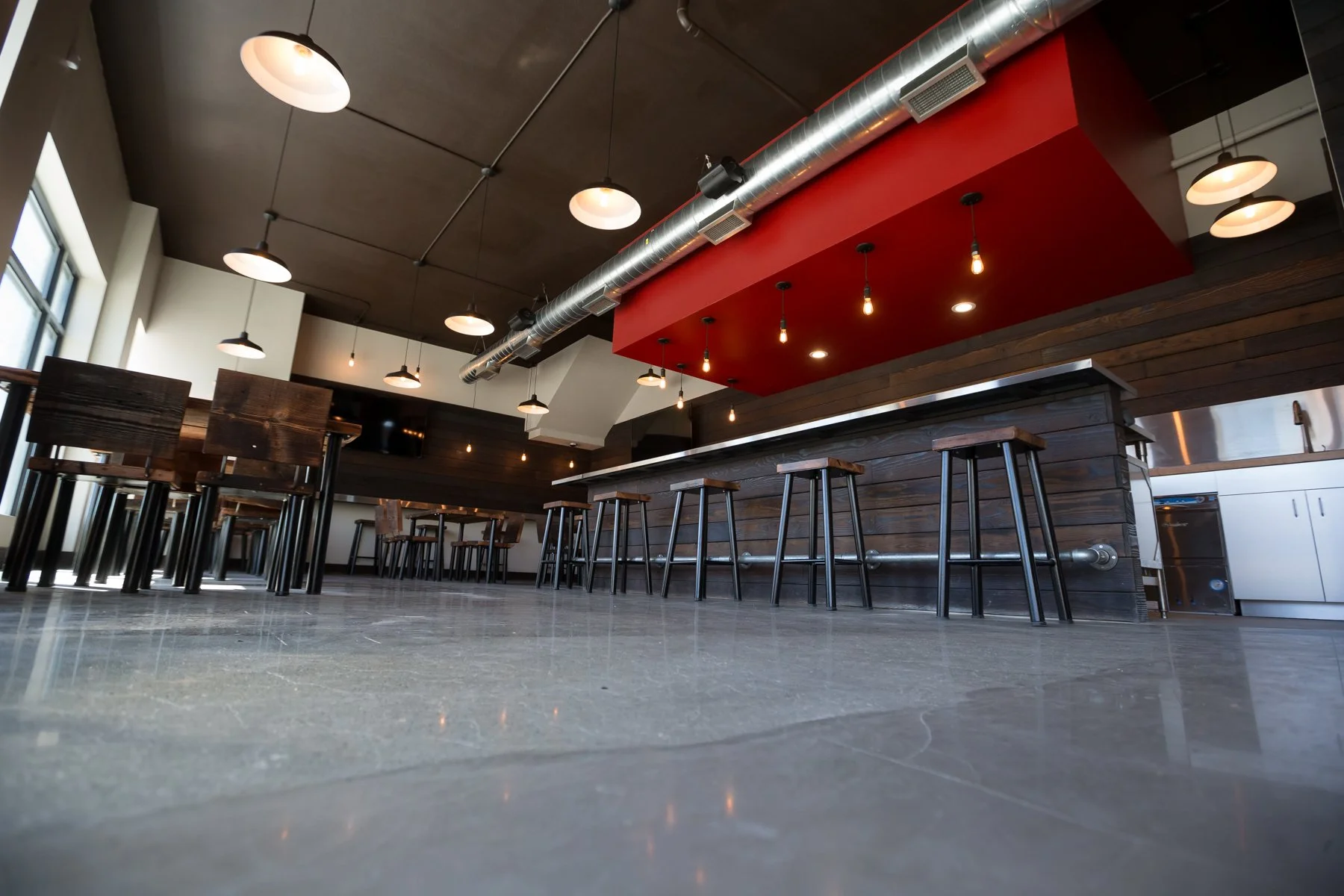 Brewery taproom with long bar and red accent soffit