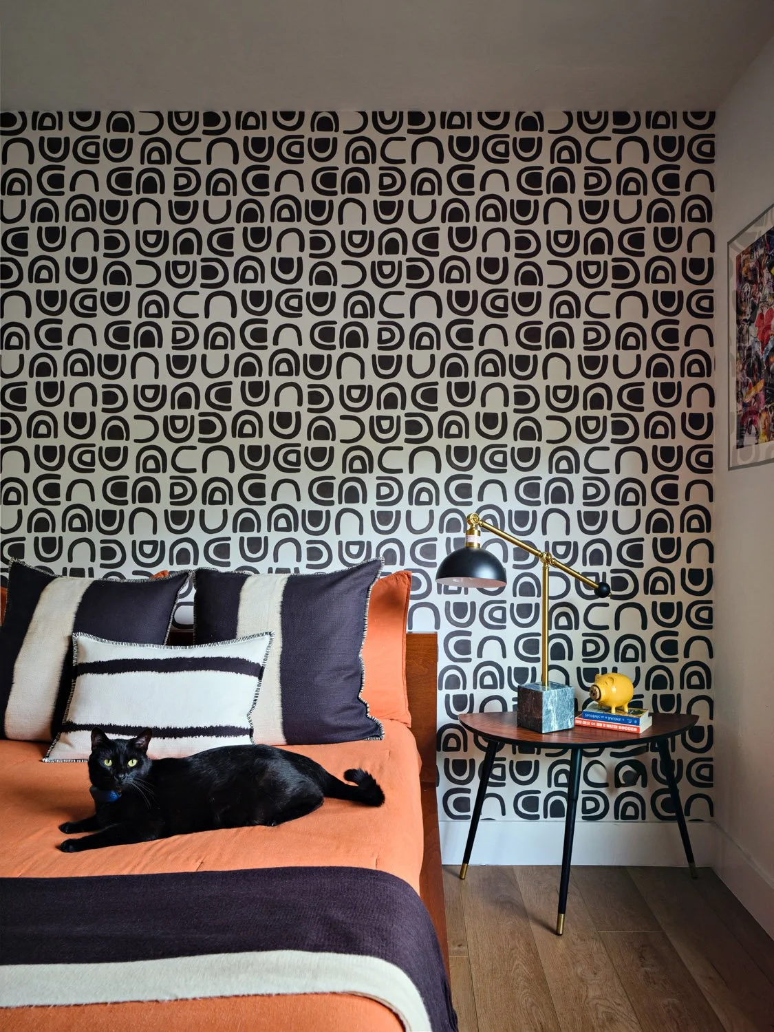 Bedroom with bold black and white wallpaper and orange bedding