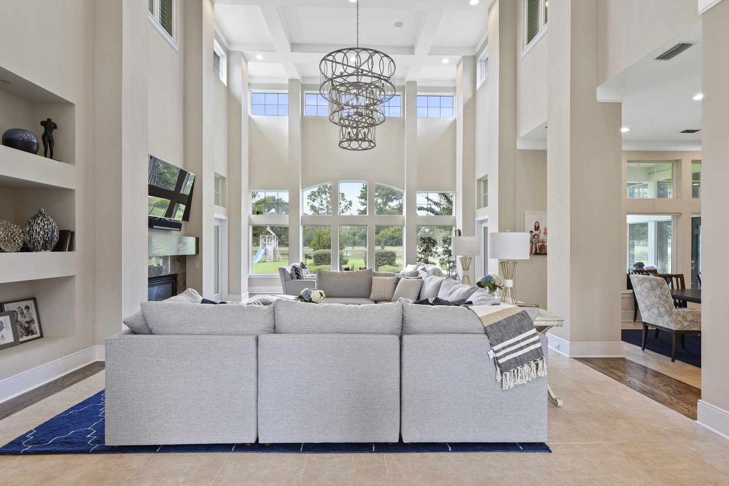 Great room with gray sectional, built-in shelves and tall windows