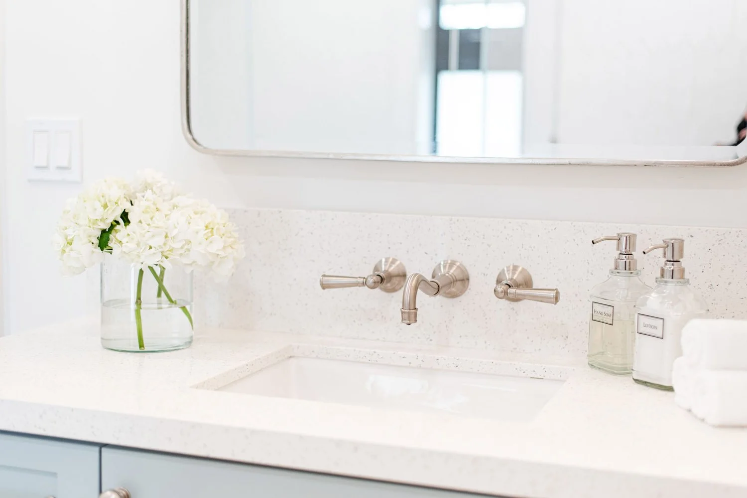 Light blue vanity with wall-mounted faucet and rounded mirror