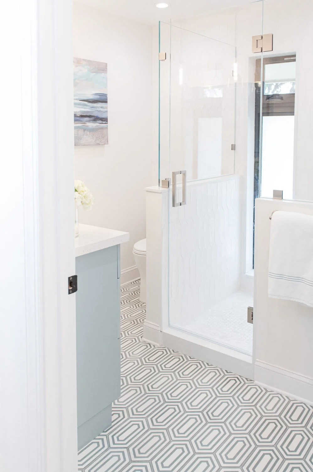 Kids bathroom with glass shower, light blue vanity and patterned floor