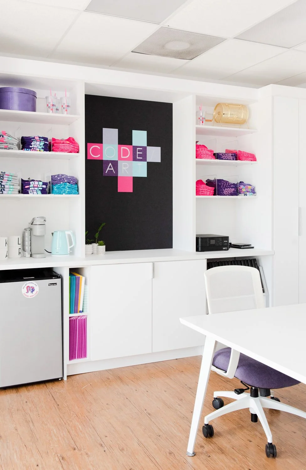 Built-in shelving with colorful bins beside a white desk