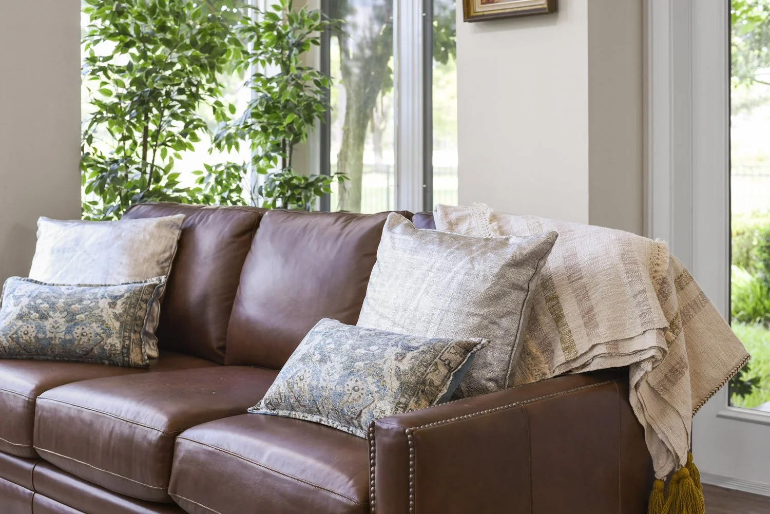 Brown leather sofa with patterned pillows and throw blanket