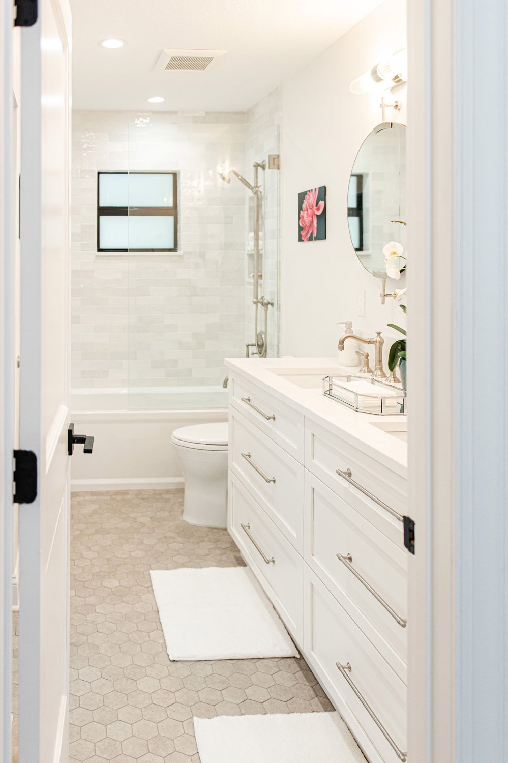 Guest bathroom with white vanity and tub with window