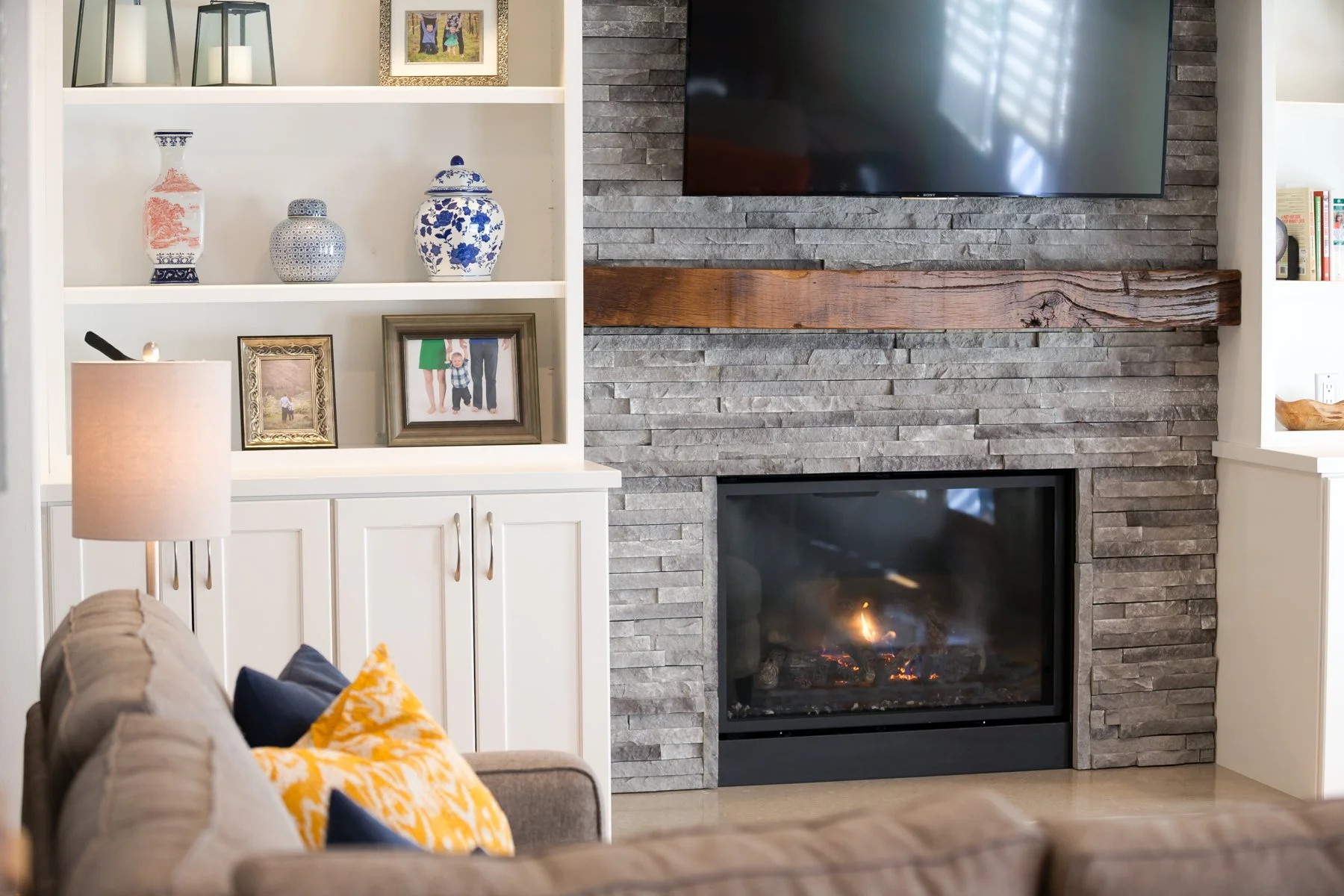 Stone fireplace with wood mantel between white built-in shelves