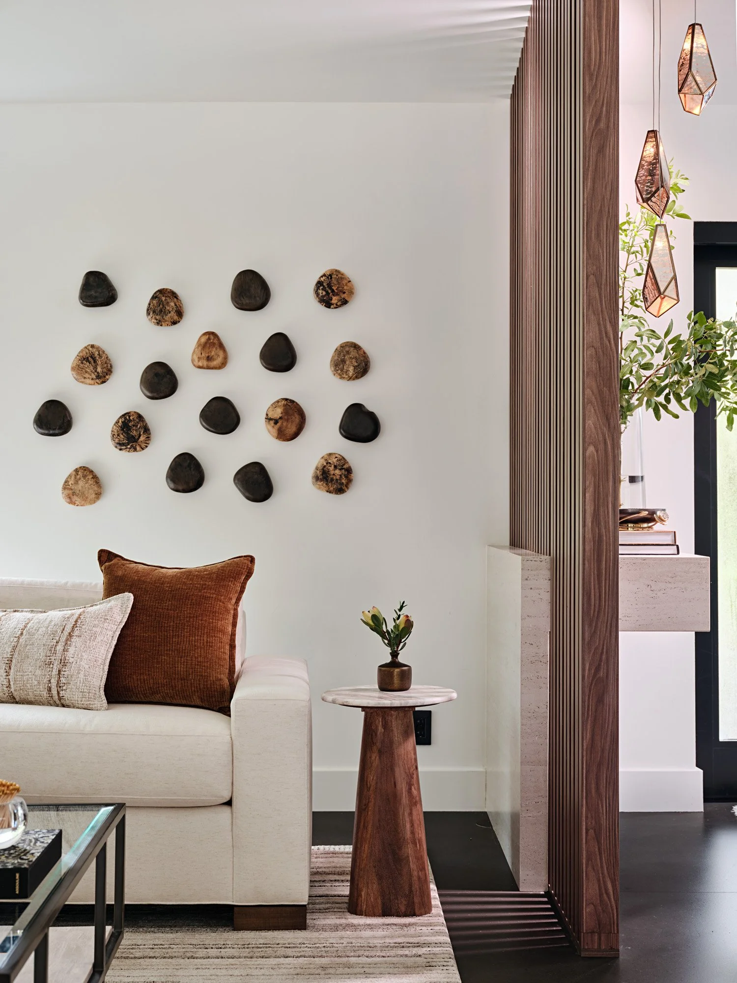Wood wall sculptures above a cream sofa with rust pillows