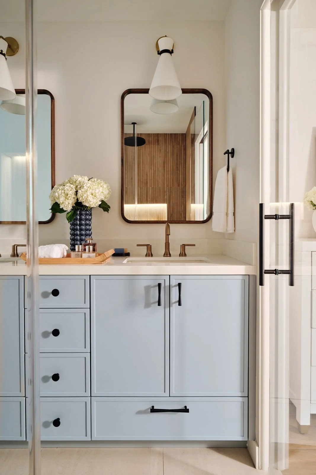 Light blue vanity with round mirror and white flowers