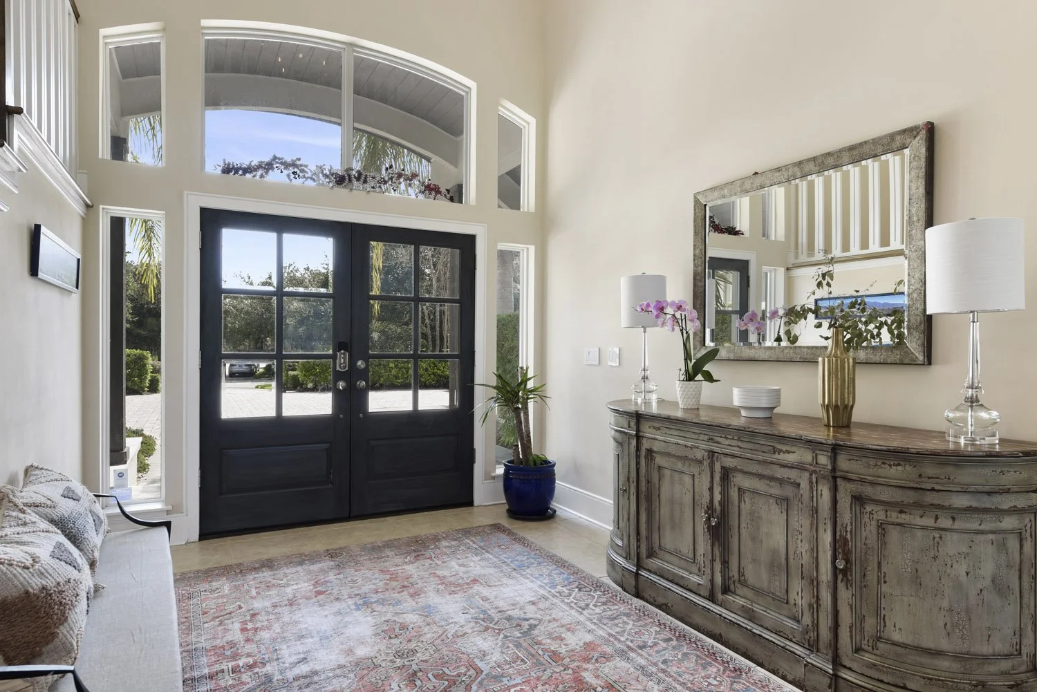 Two-story foyer with black double front doors and distressed wood console