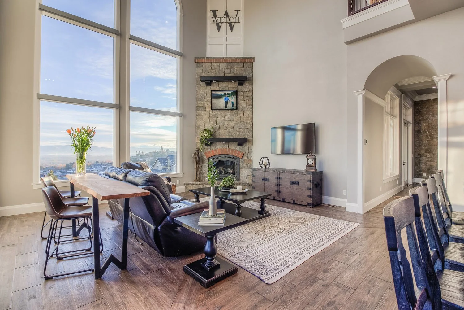 Living room with stone fireplace, tall windows and arched doorway