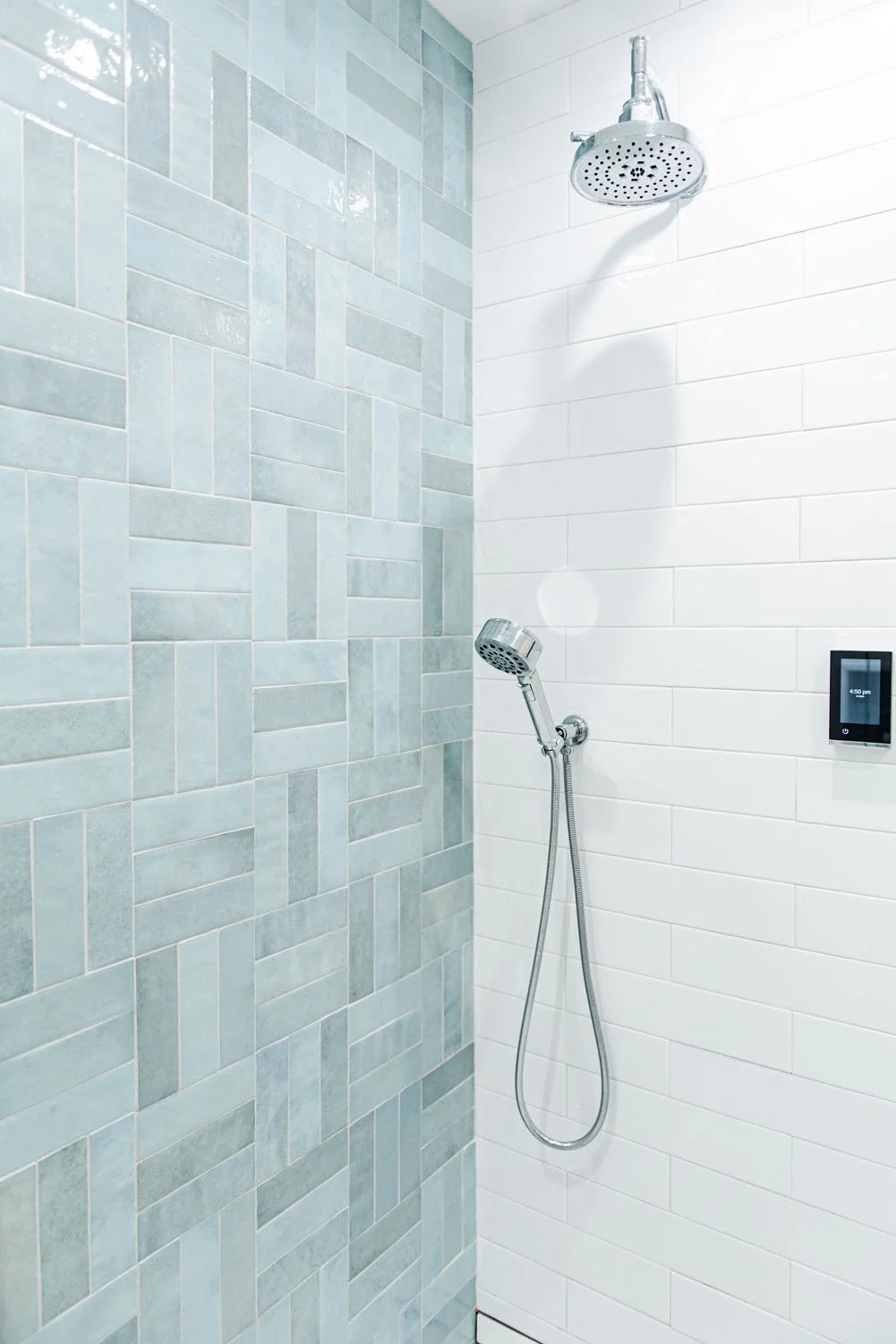 Shower with blue herringbone tile and handheld shower head