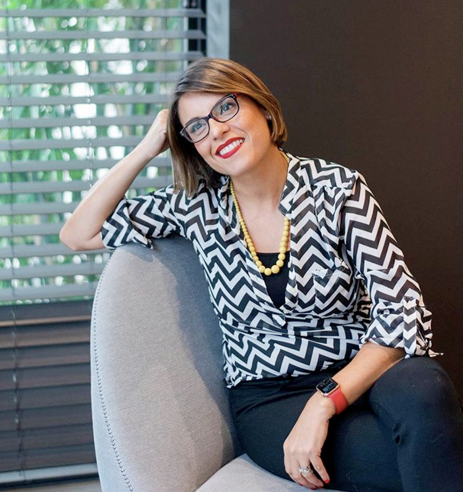 Interior designer Adriana Jacir seated in a gray armchair