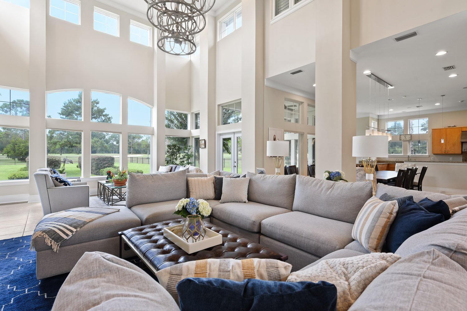 Great room with gray sectional, navy rug and tall windows