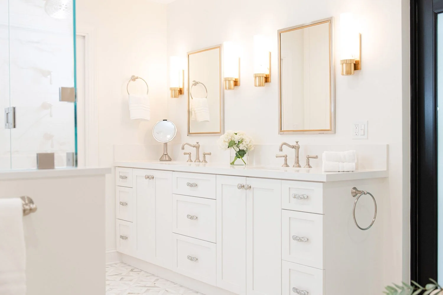 White double vanity with mirrors and brass sconces
