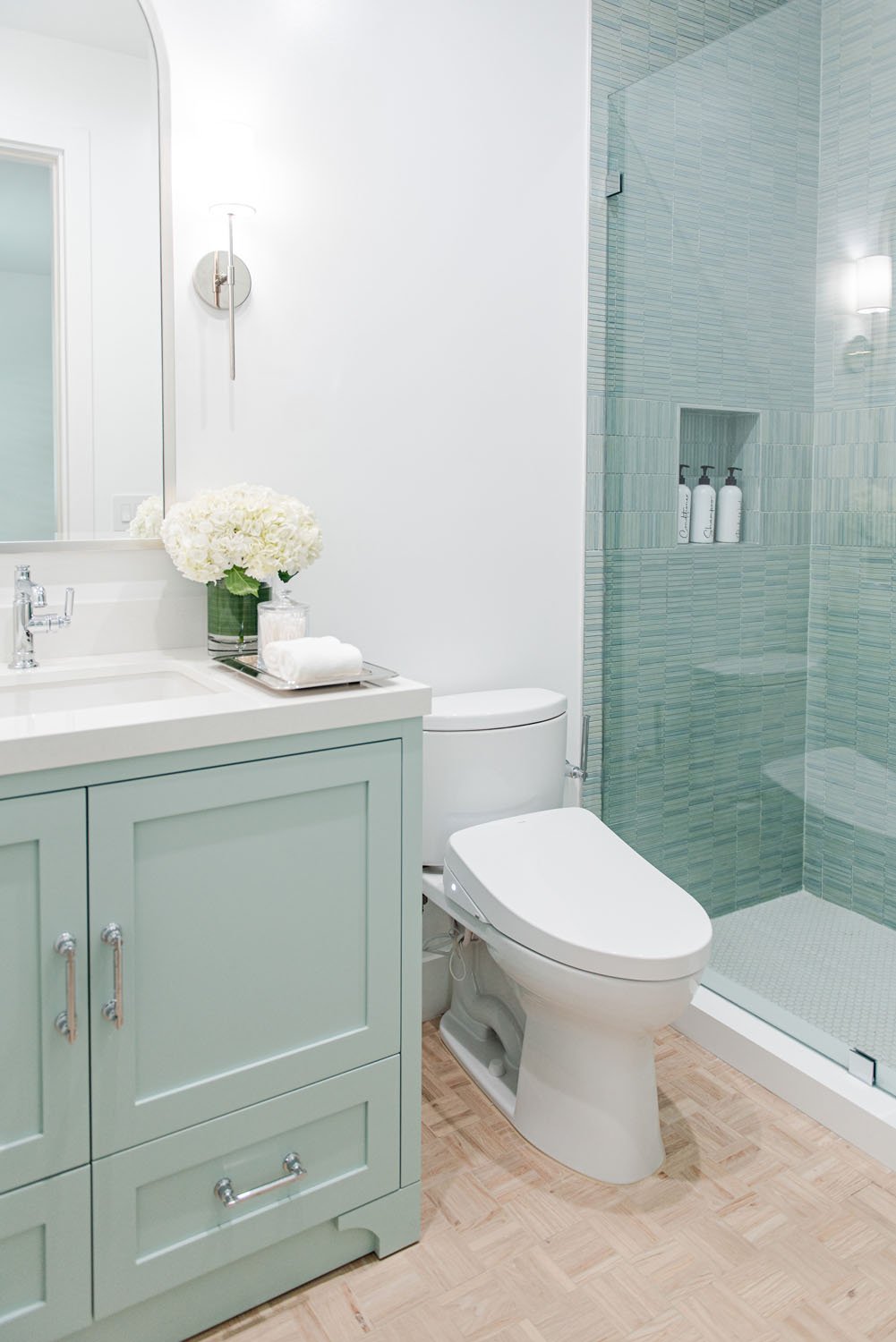 Bathroom with sage green vanity, toilet and glass shower