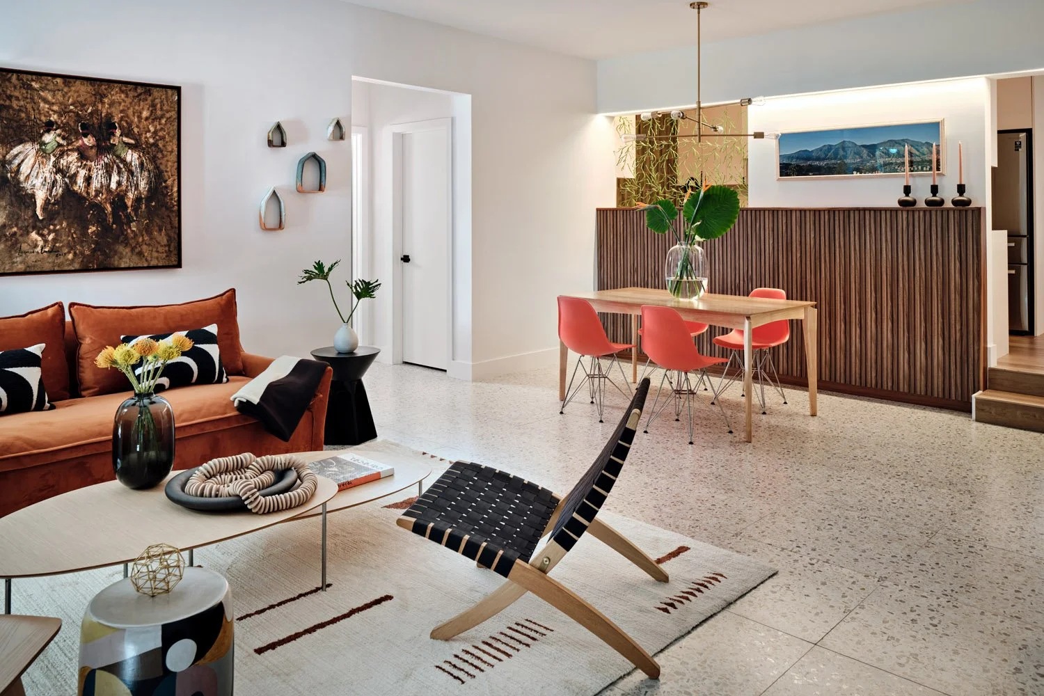 Open living and dining area with terrazzo floors and coral dining chairs