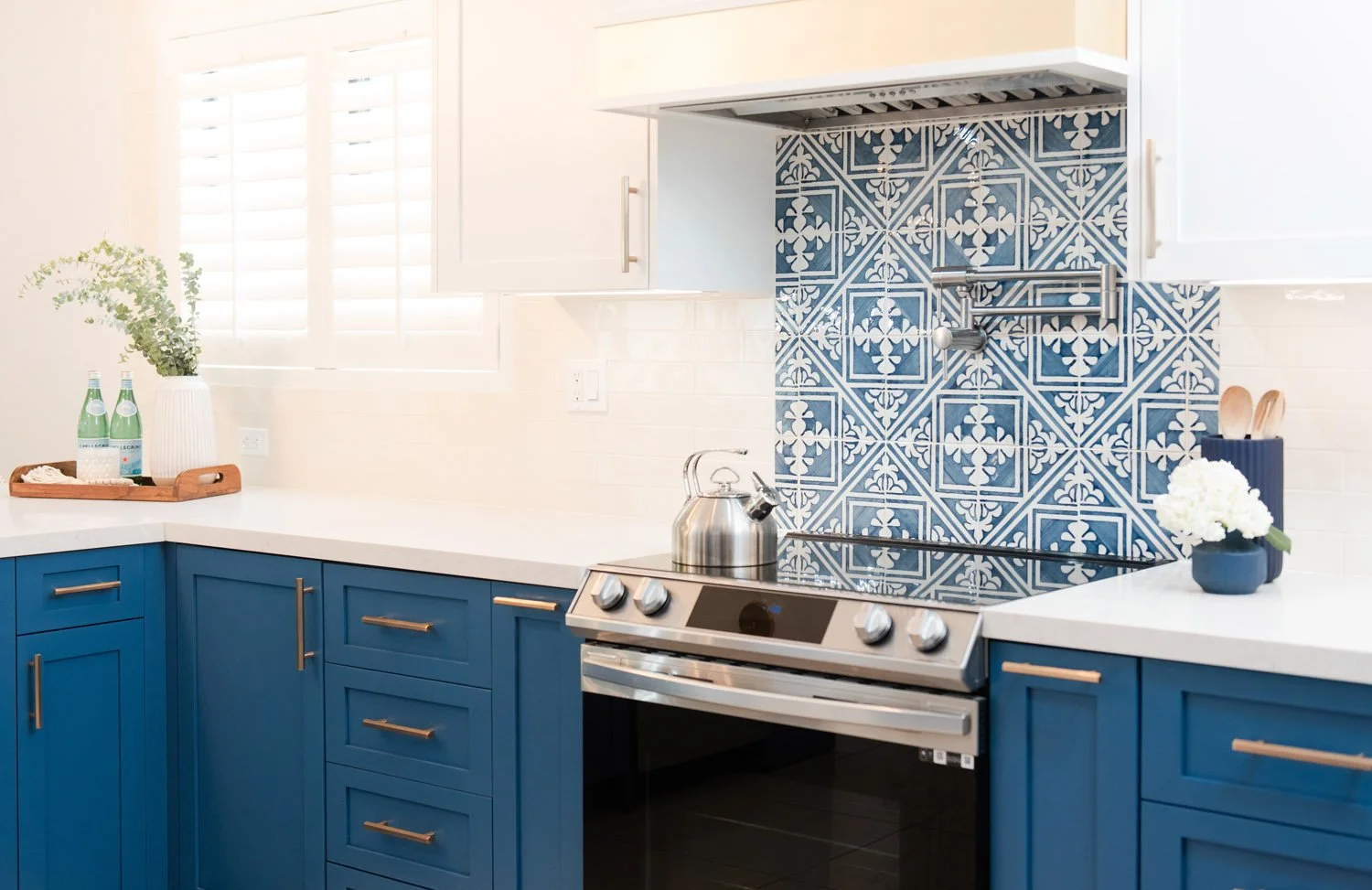 Navy cabinets with blue patterned tile and stainless range