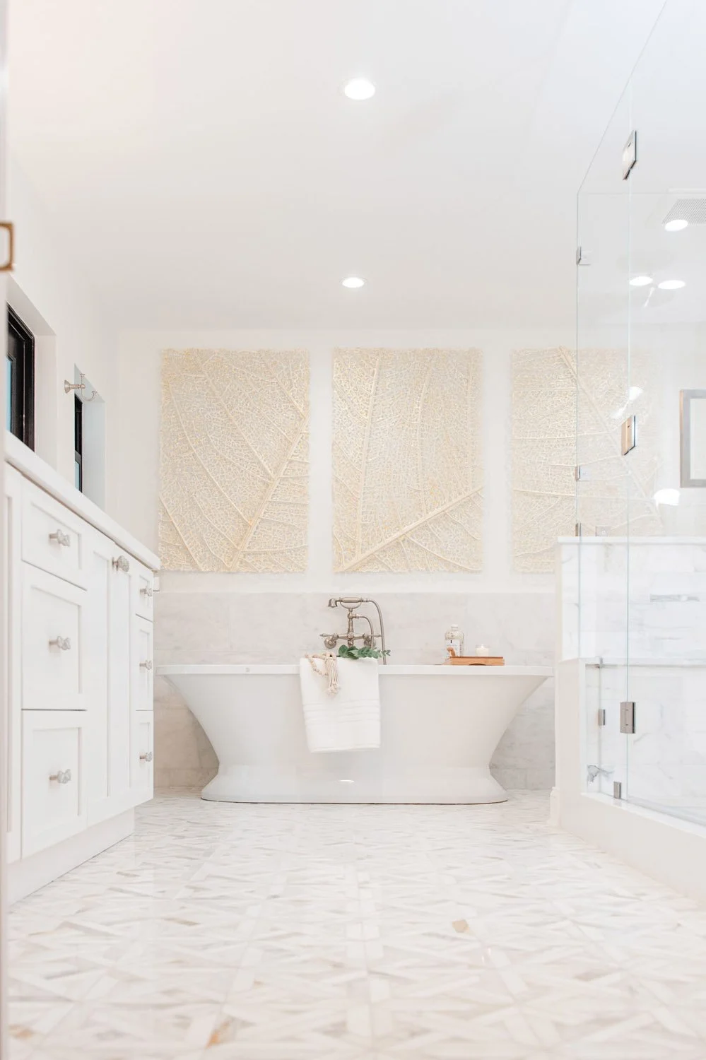 White bathroom with freestanding tub and tall linen cabinets