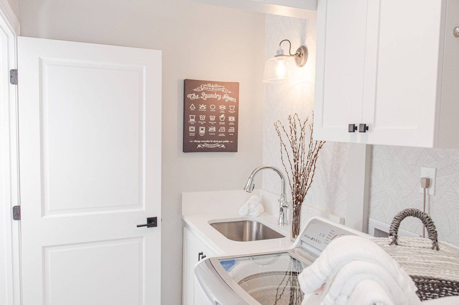Laundry room with utility sink and white cabinets