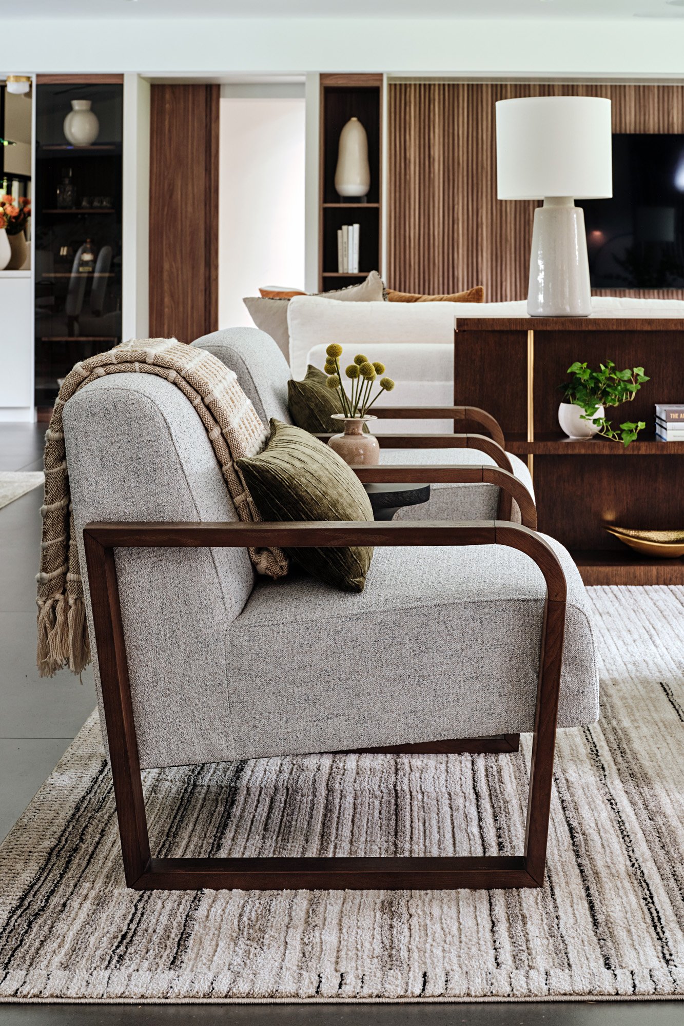 Cream armchair with walnut frame in front of a dining area