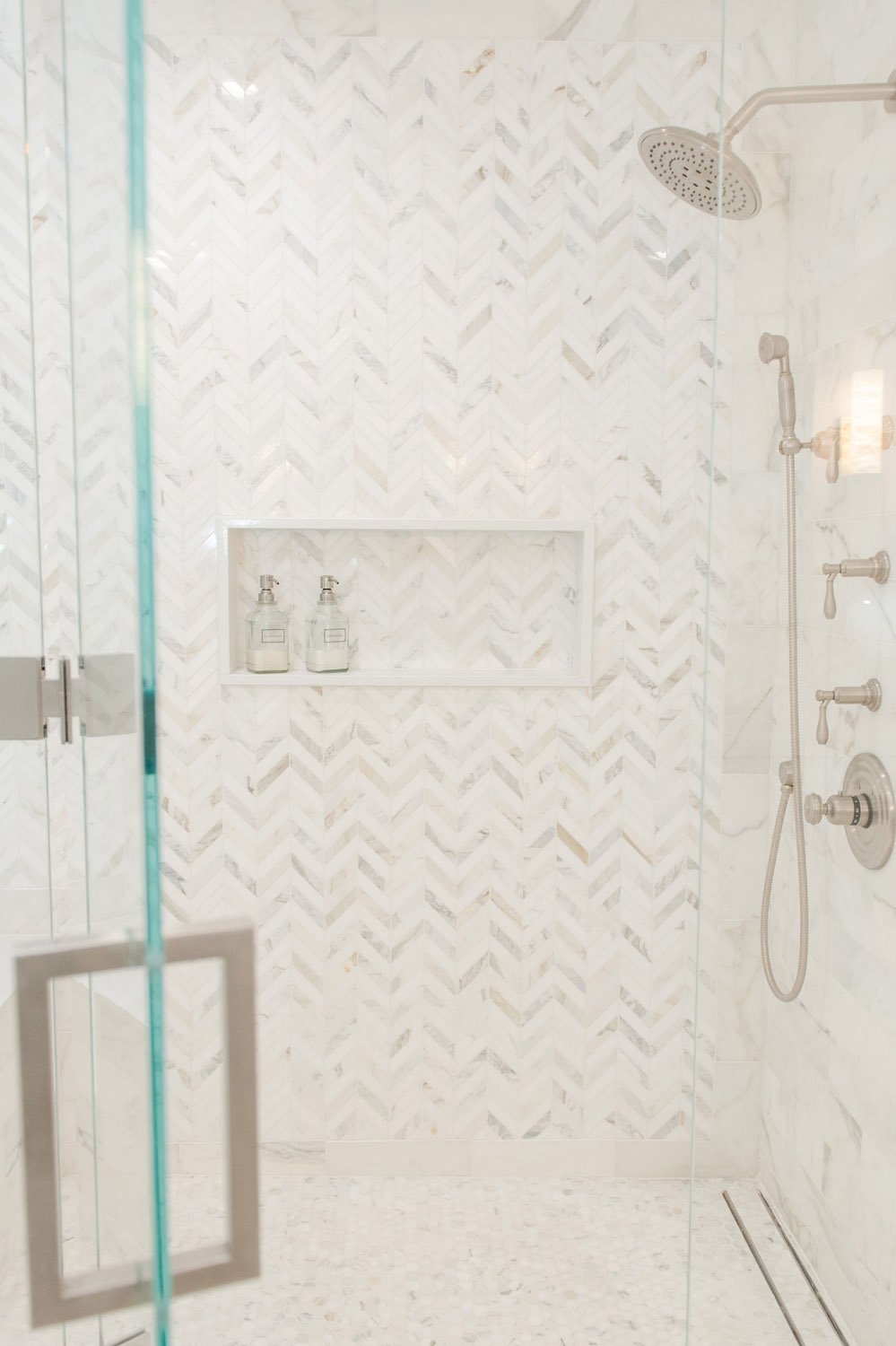 Marble walk-in shower with built-in niche and glass door
