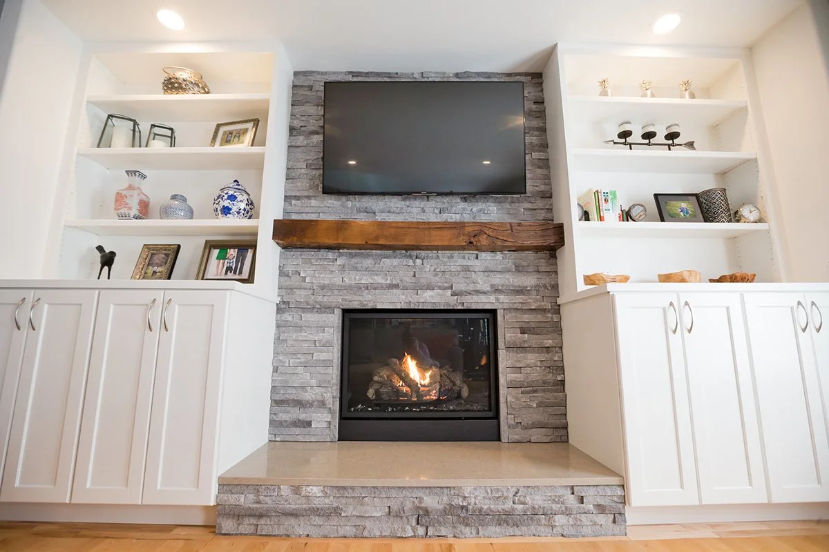 Stone fireplace with white built-in shelves and gray sofa