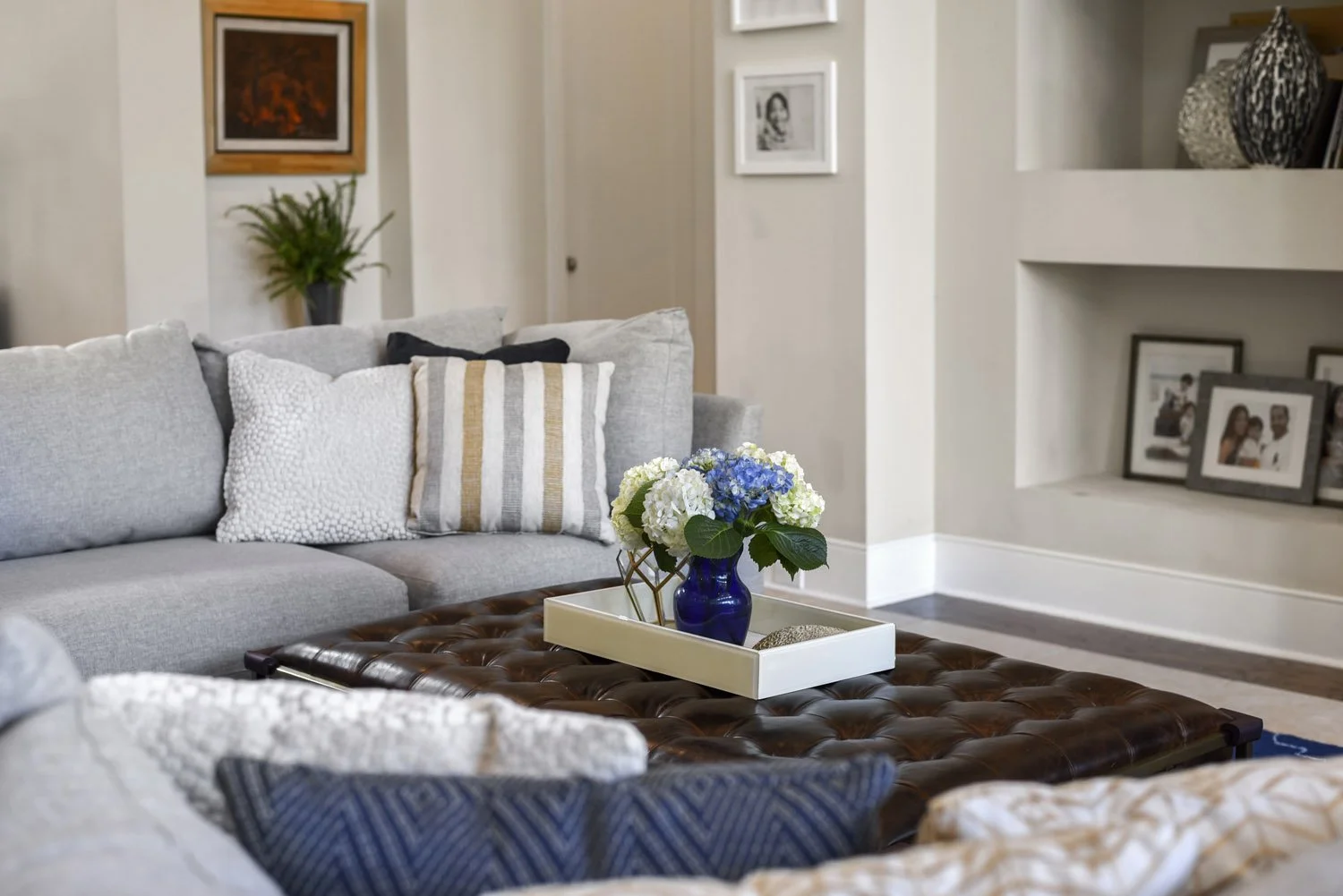 Gray sectional with throw pillows, built-in shelves and leather ottoman