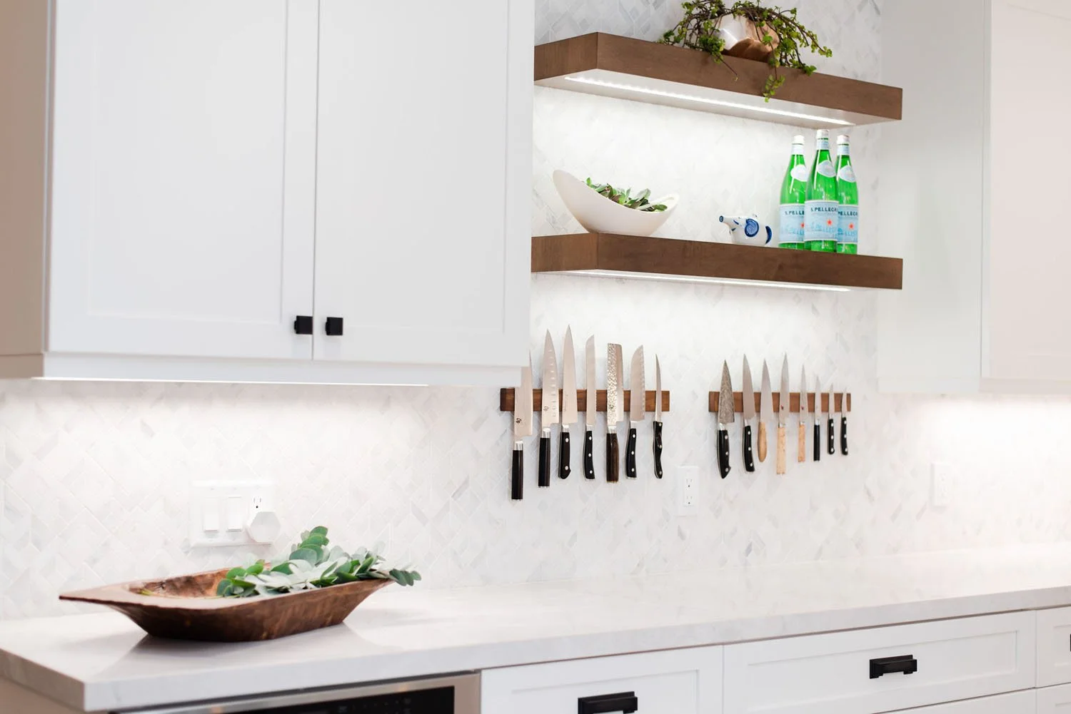 Floating walnut shelves above a magnetic knife strip and quartz counter