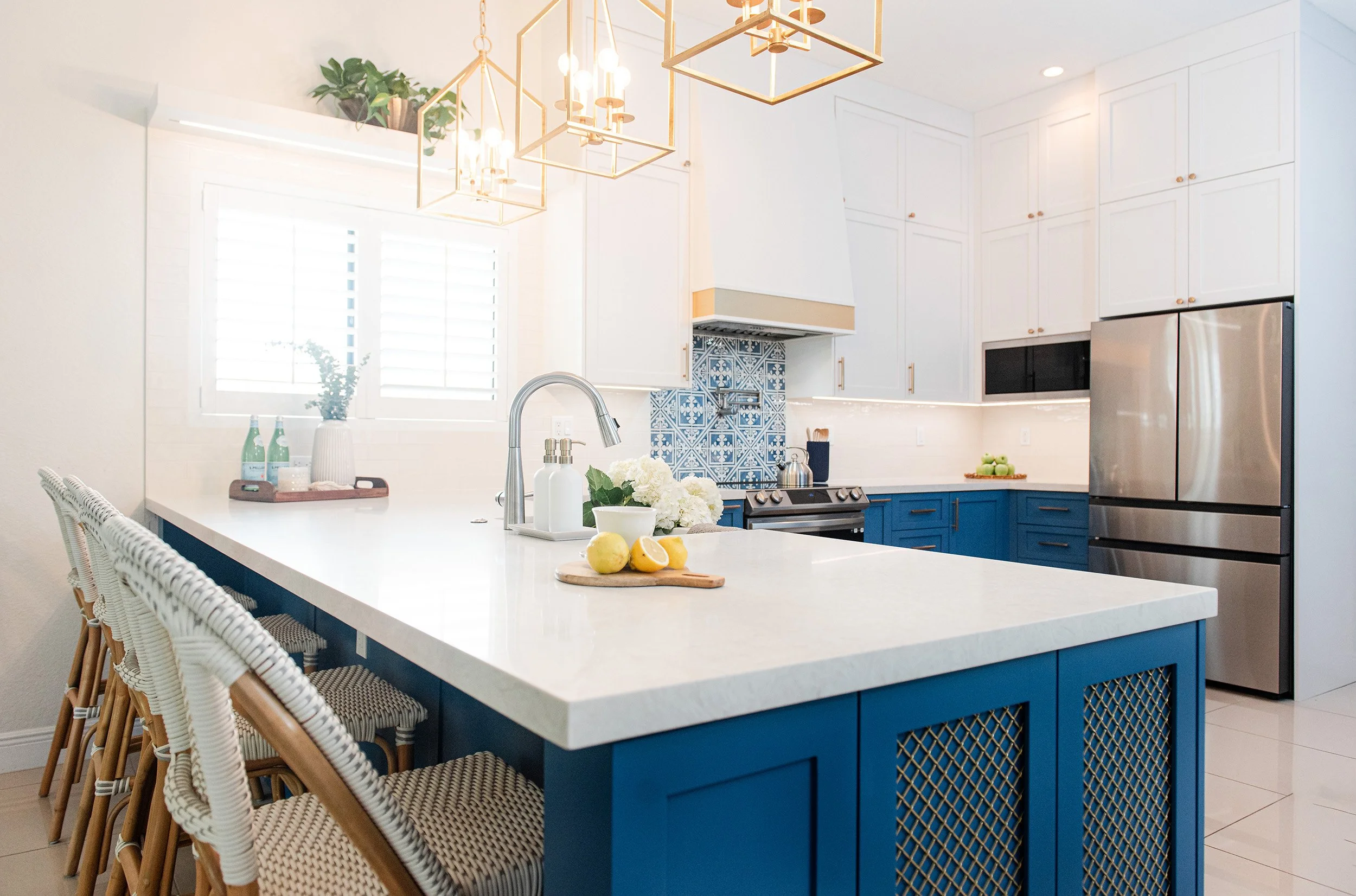 Navy kitchen island with white quartz top and brass pendants