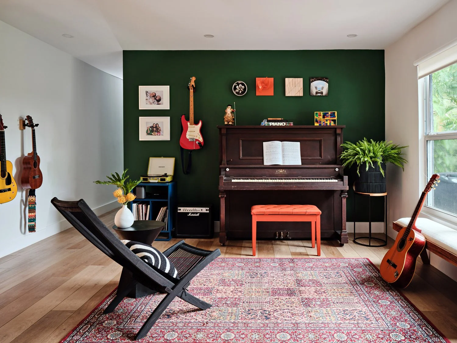 Music room with upright piano, guitars and green accent wall