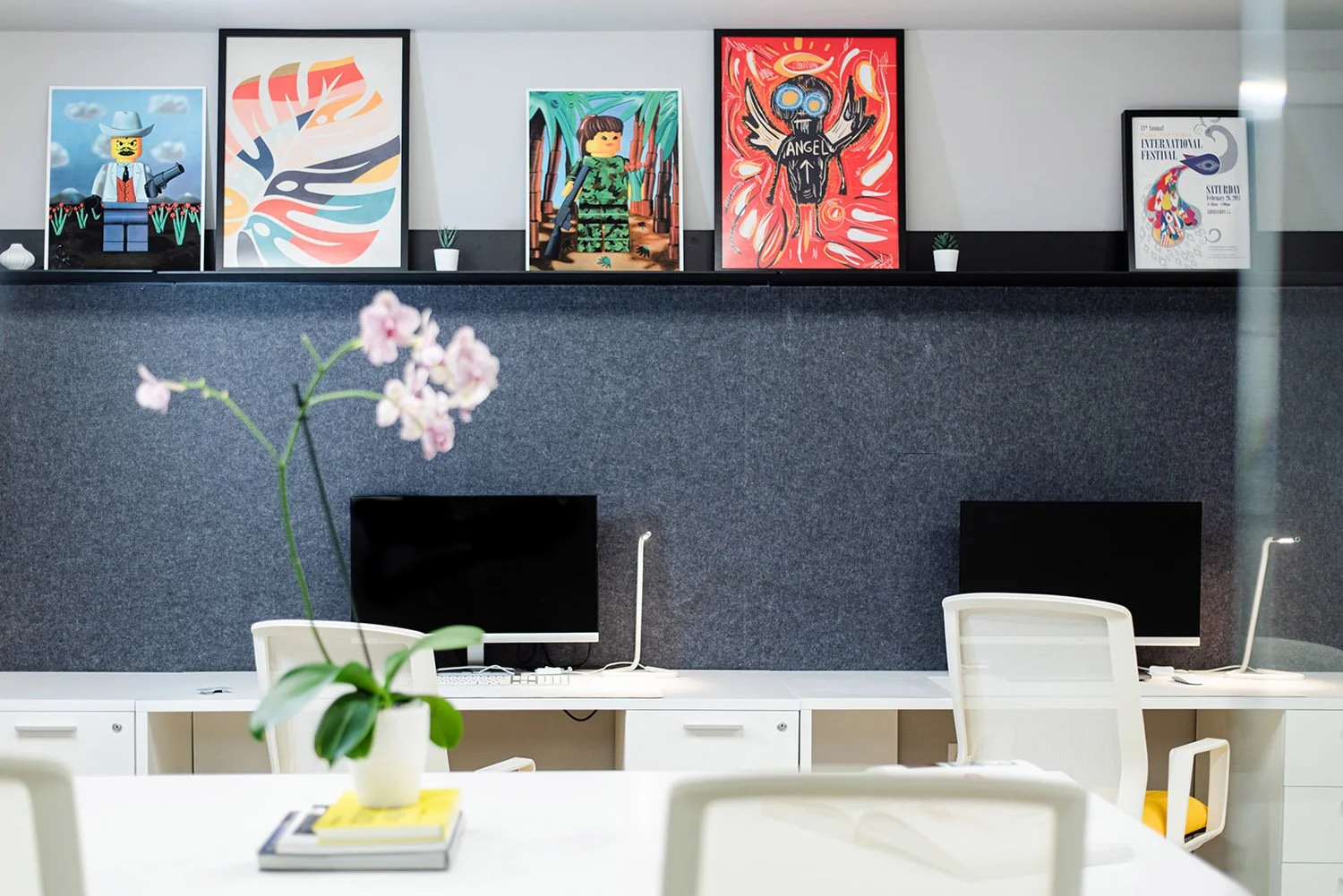 Office desks with framed colorful posters and orchid