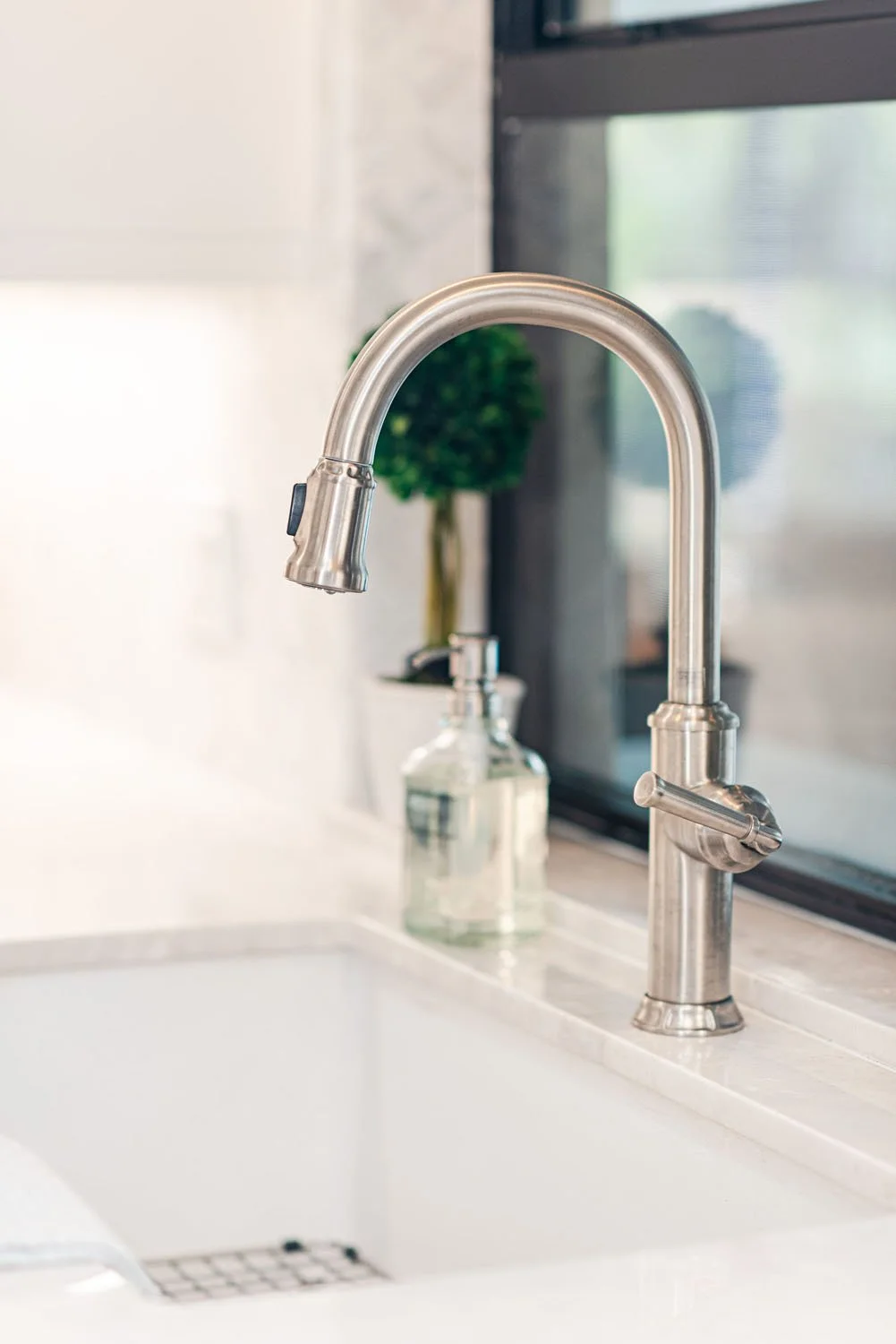 Brushed nickel faucet over an undermount sink by a black window
