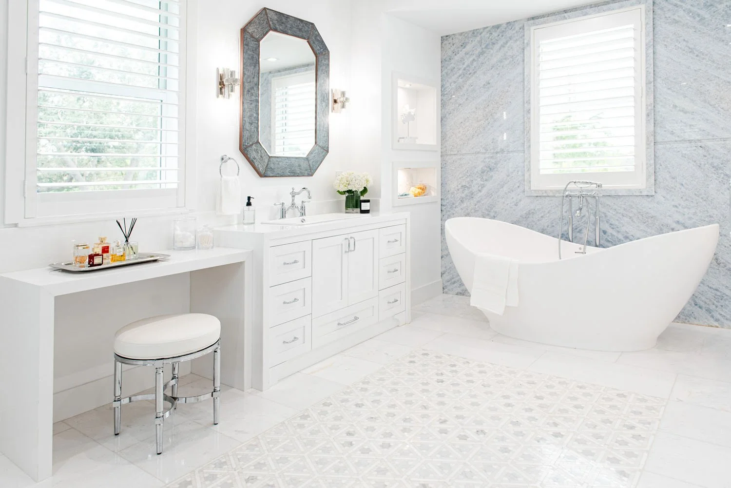 Primary bathroom with freestanding tub, makeup vanity and marble walls