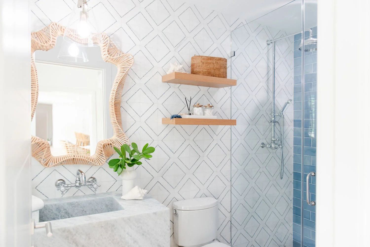 Bathroom with rattan wave mirror, marble sink and blue tile shower