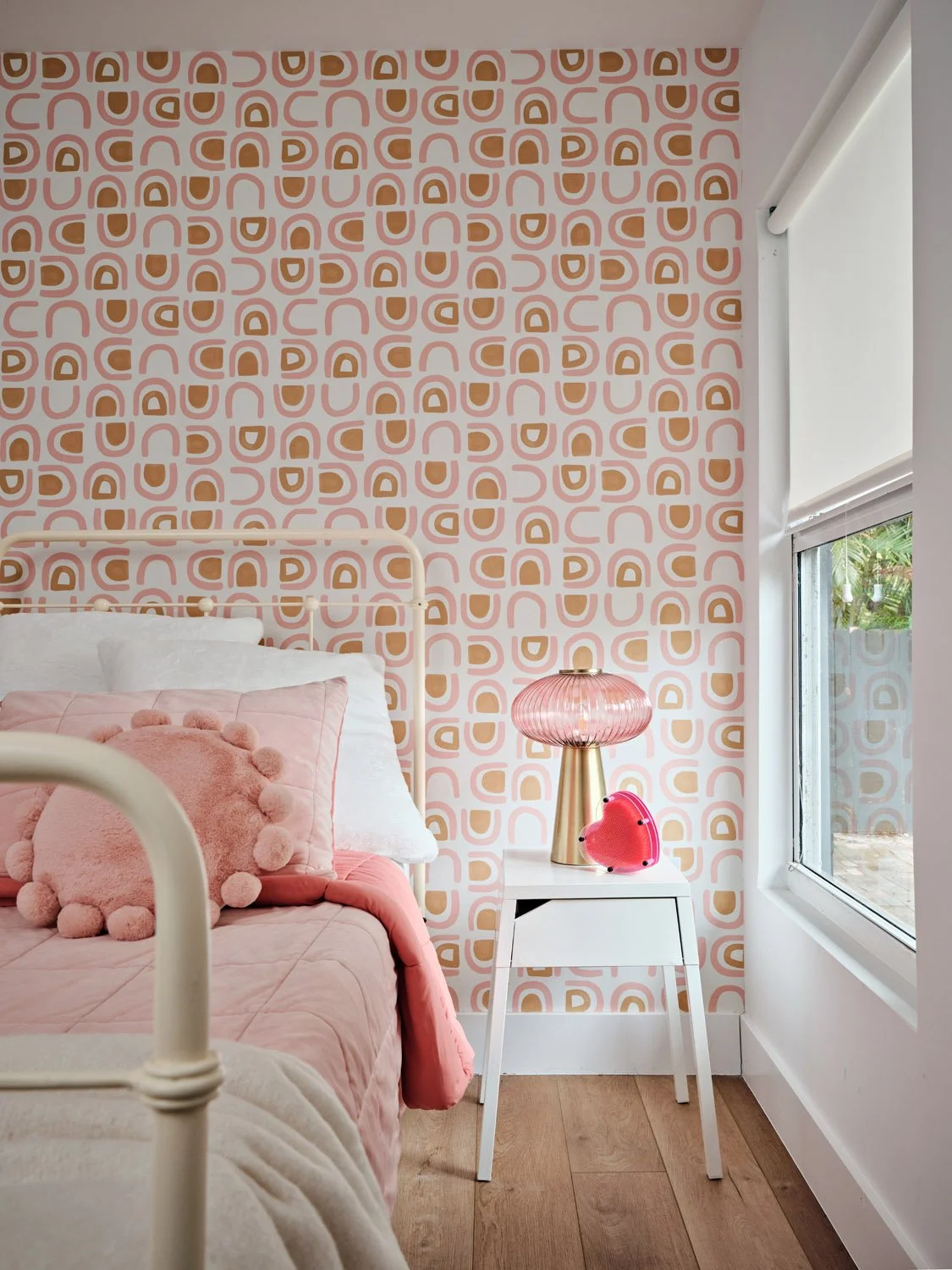 Pink bedroom with patterned wallpaper and white metal bed