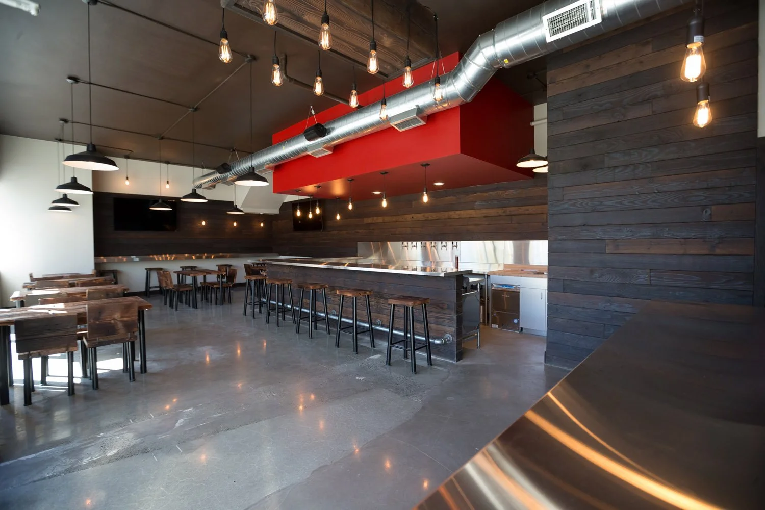 Open taproom with concrete floor, bar and seating